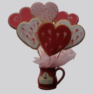 Heart cookies on skewers to make a cookie bouquet in a red mug with the Chehalem Ridge B&B logo on it