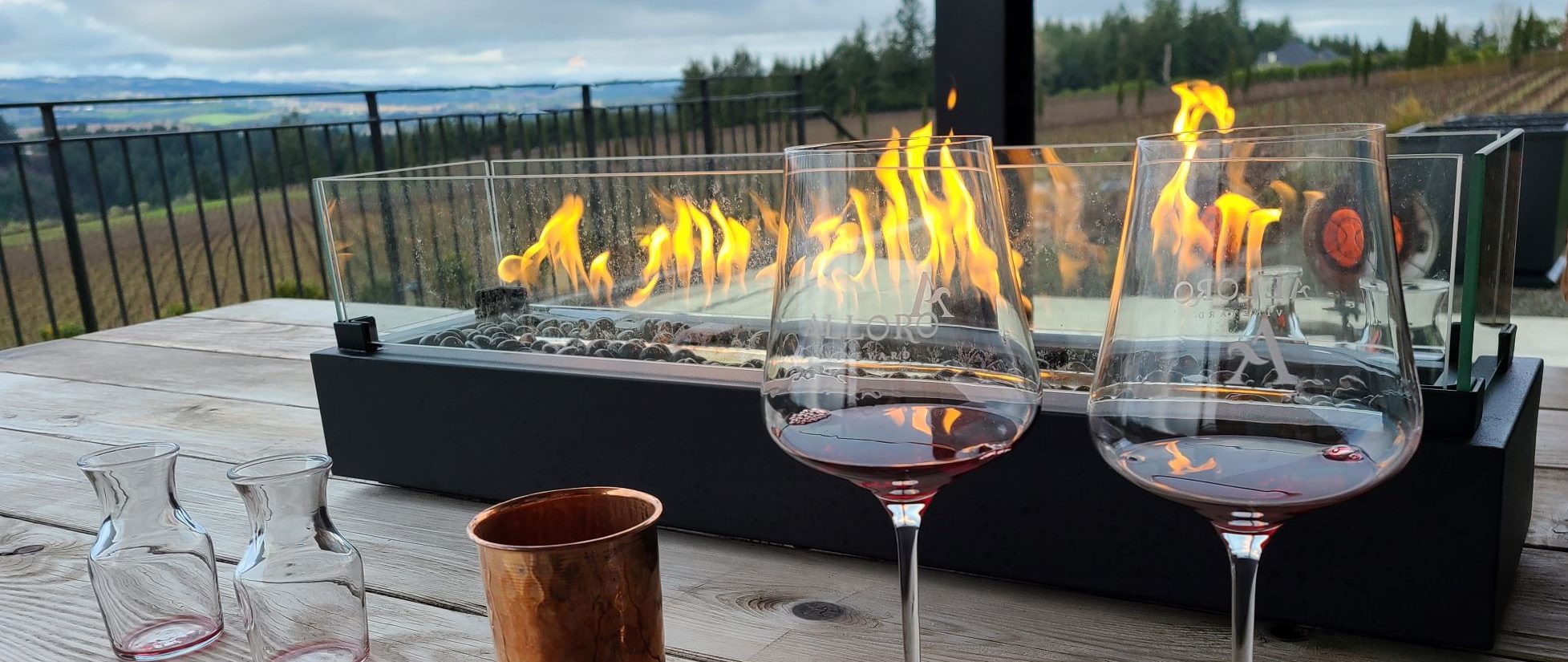 two glasses in front of an in-table fire feature overlooking vineyards