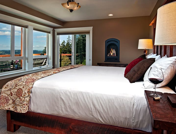 High Desert Suite, a bed with white sheets, a fireplace inset in the wall and windows looking out to the valley