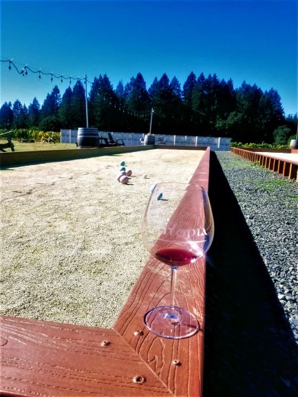 a glass of wine on the ledge of a bocce ball court