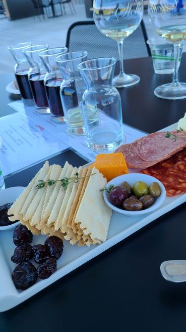 a charcuterie board with vials of wine behind