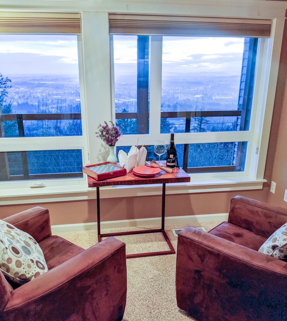 two chairs facing windows with a view and a table with take-out dinner
