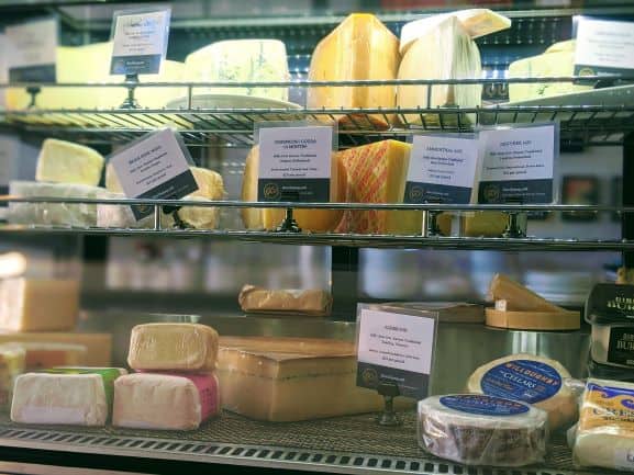 A deli case with three shelves of cheese