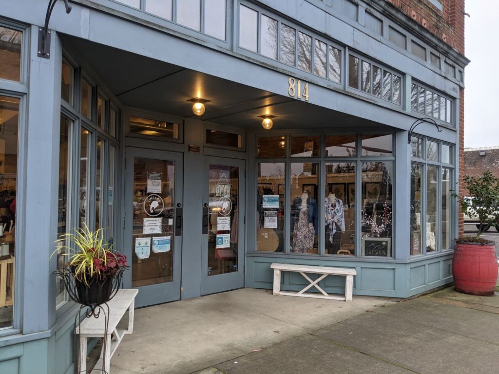 A block-long section of shop window with a bench outside on sidewalk, in Newberg, Oregon.