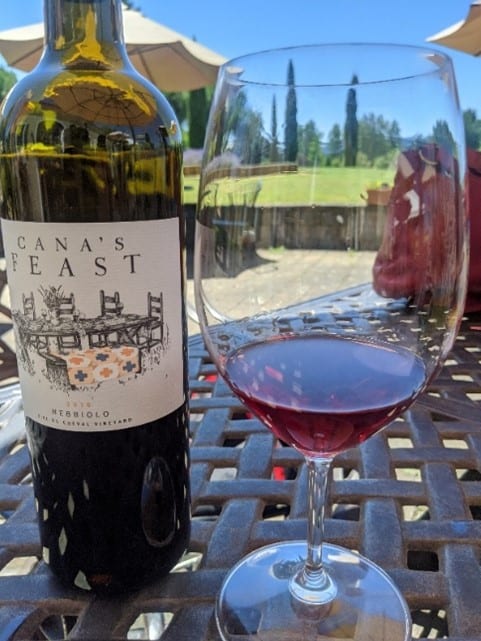 A glass and bottle of wine on a patio table outside in the Willamette Valley