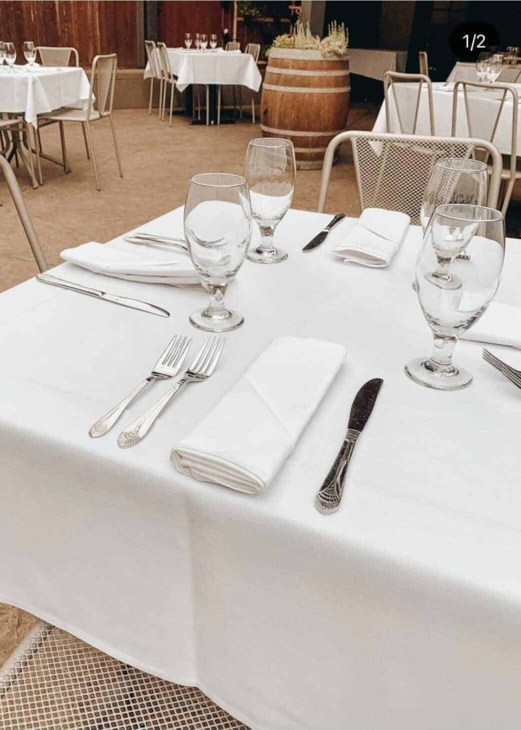 a table with white tablecloth, set for dinner in a patio setting