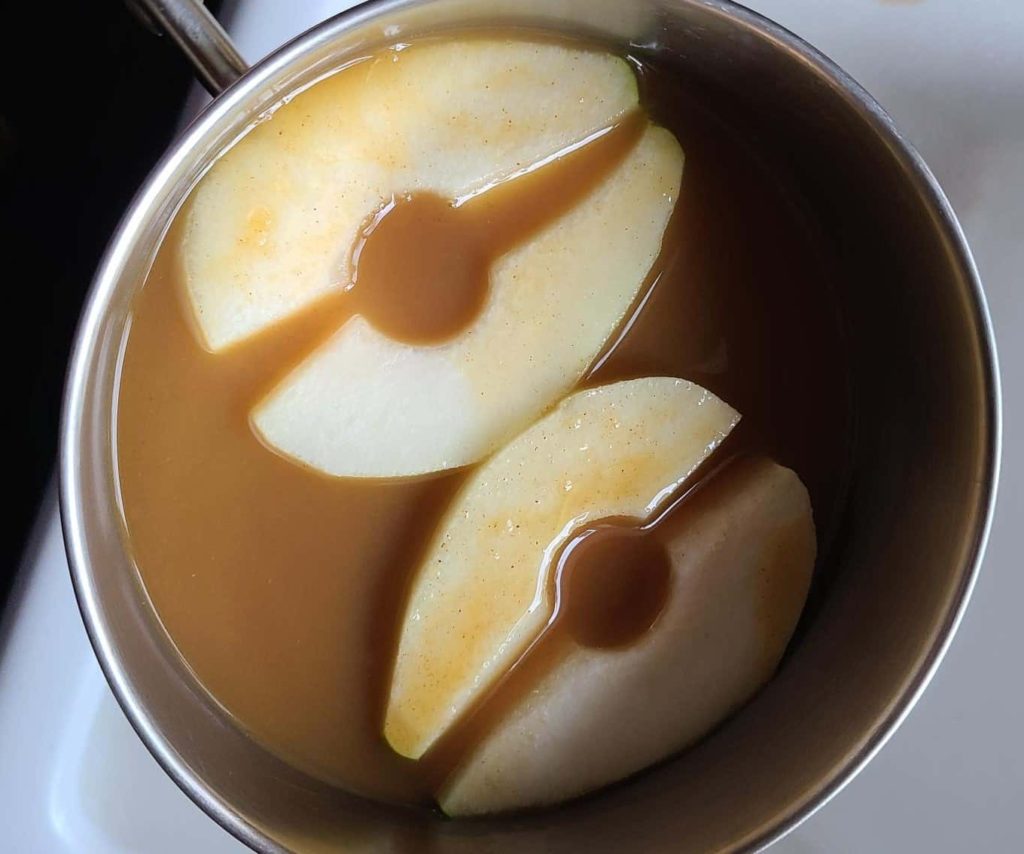 two pear halves in a brown liquid in a small pot
