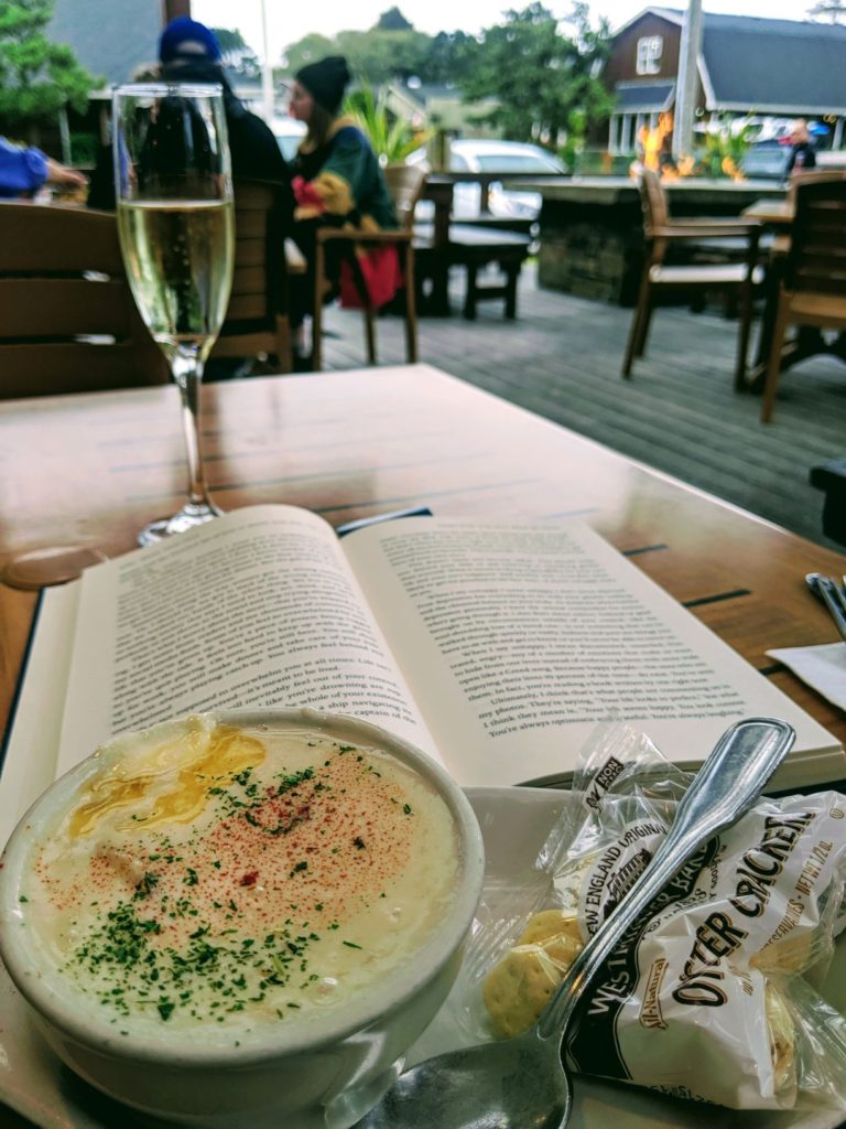 A table at an Oregon Coast restaurant with soup, crackers, a book and a glass of wine.