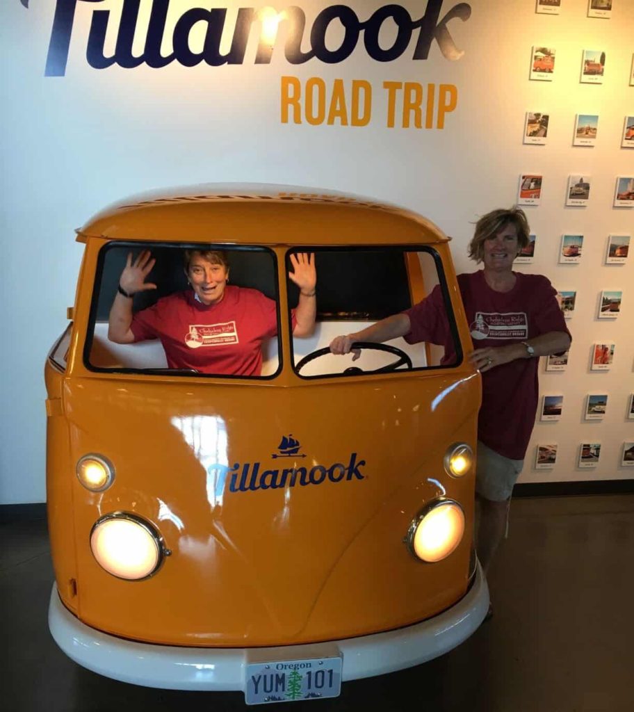 a VW bus painted Tillamook yellow with the Tillamook logo on it and two women posing