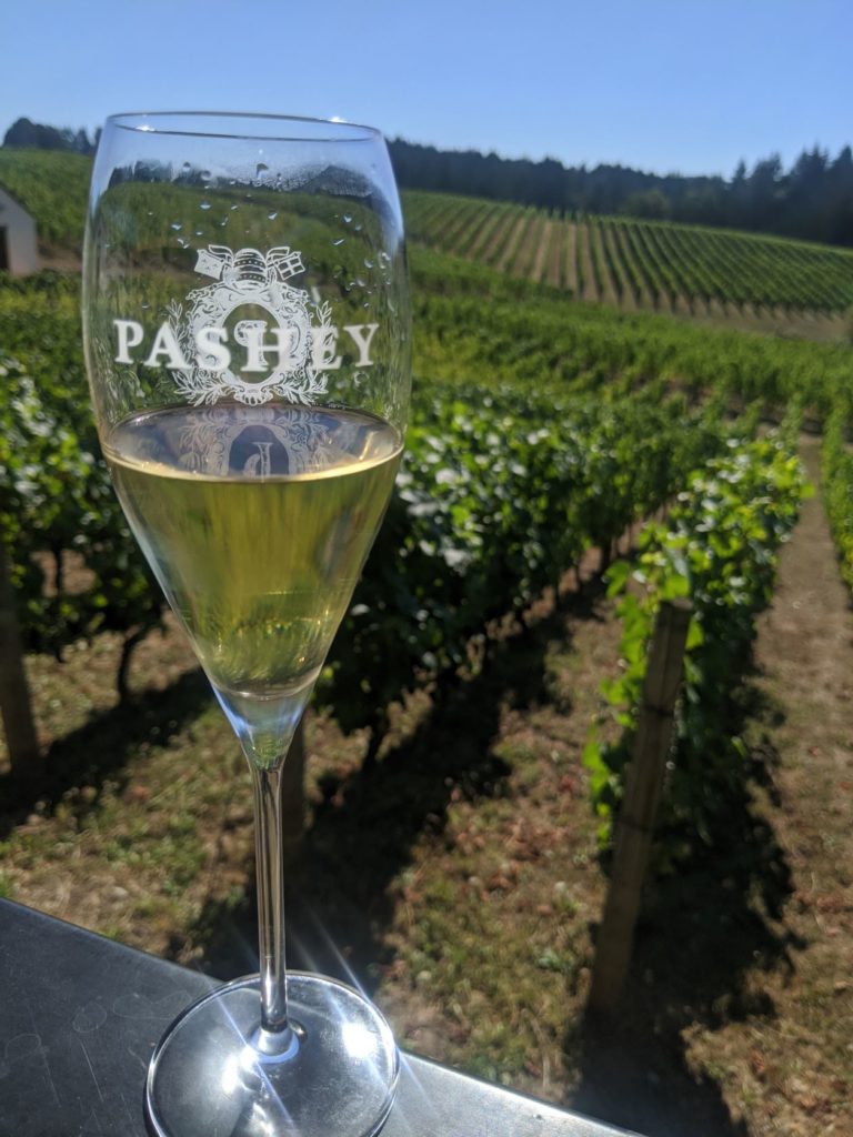 a skinny wine glass holding Oregon Sparkling wine from the Pashey label of Trisateum