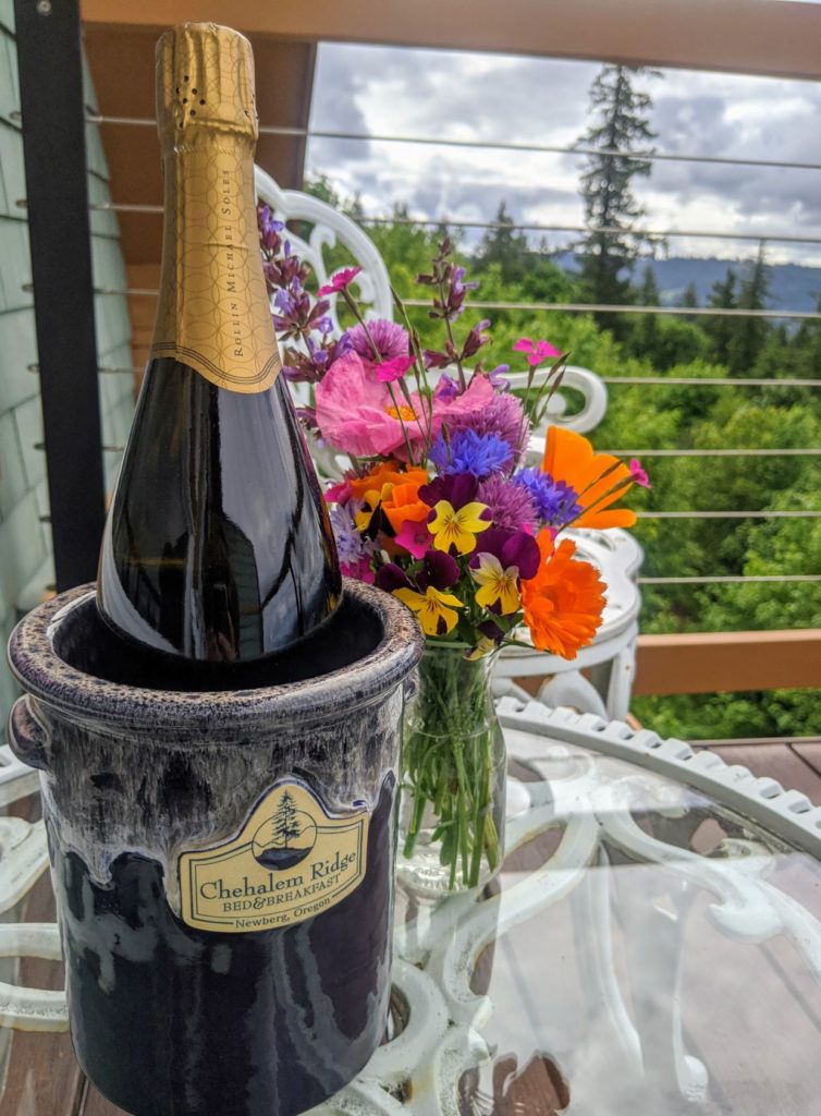 a wine chiller with Chehalem Ridge B&B logo on it holding a bottle of Roco Sparkling wine on an outside tabel