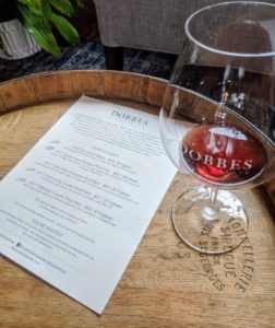 a glass of pinot noir atop a barrel with the wine tasting menu