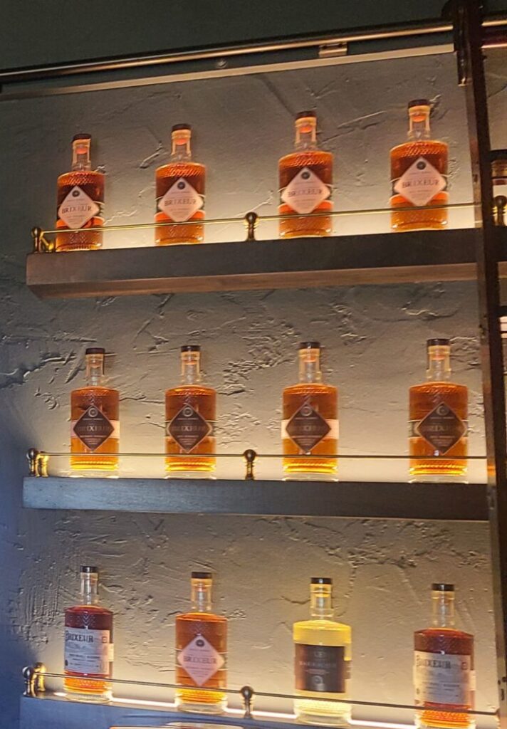 Three shelves on a wall with liquor bottles on the shelves. The bottles all are labeled with Brixeur Distillery, a Willamette Valley distillery