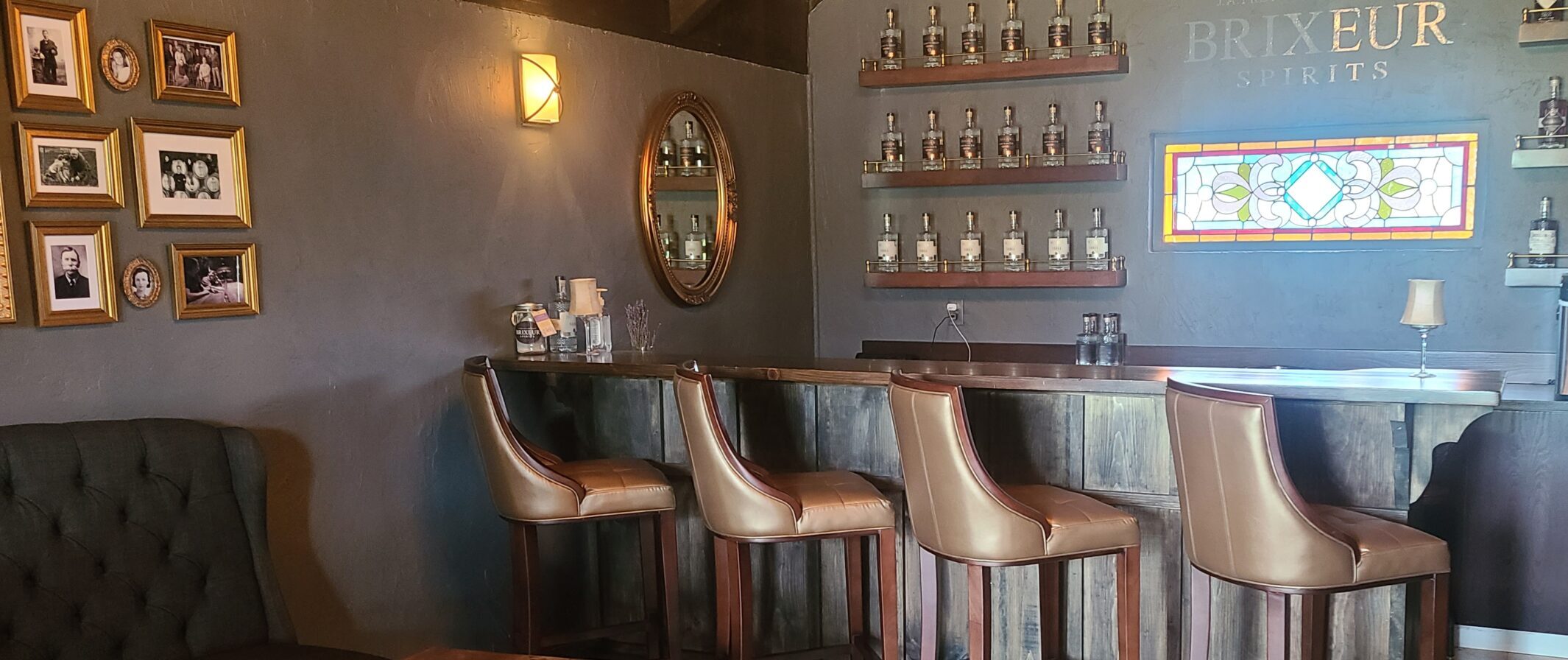 four leather chairs siting at a bar with liquor bottles on wall shelves at a willamette valley distillery