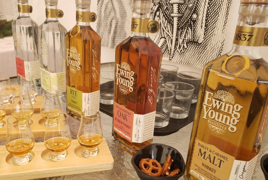 5 bottle so liquor lined up on a counter with small glasses for tastings. Each bottle is labeled Ewing Young Distillery, a willamette valley distillery