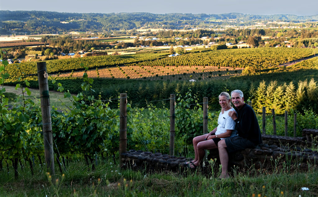A woman and man standing in front of Anderson Family Vineyards fields with a view of the valley in the background
