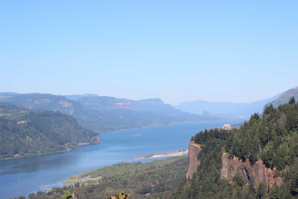 The Columbia River Gorge seen from Women's Forum State Scenic Overlook, with the river and the Vista House, an octagonal building, on a cliff to the right of the river